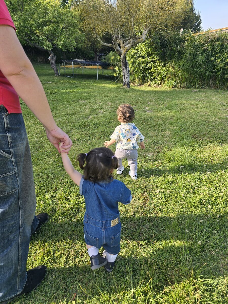 As gêmeas de costas explorando o jardim
